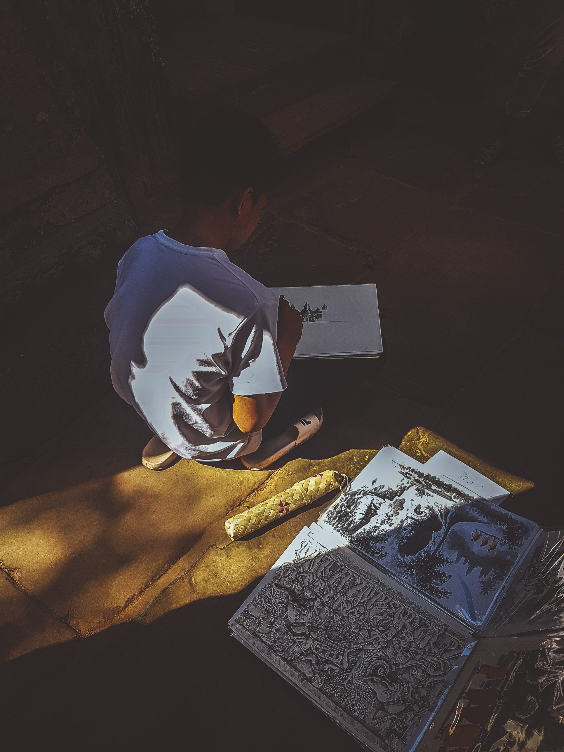a child sitting outside Angkor Wat starting to sketch